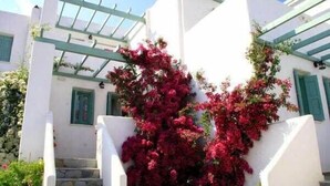 A white building with green shutters and a staircase.