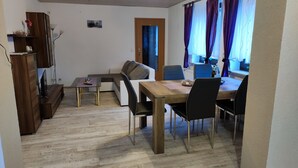 A compact living space with a dining table, chairs, a sofa, a small table, and a cabinet. - Holiday home in the beautiful Ore Mountains (Sehmatal)