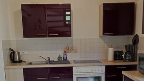 A modern kitchen with dark cabinets, a built-in oven, and a coffee maker. - Holiday home in the beautiful Ore Mountains (Sehmatal)