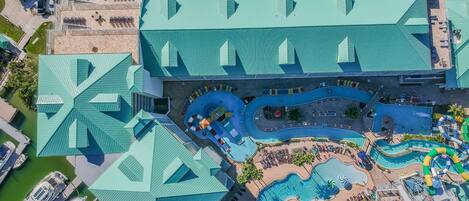 Ett flygbildsfoto av ett semesterområde med en stor swimmingpool, flera vattenrutschkanor och en parkeringsplats med flera bilar.