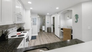 Una cocina moderna con armarios blancos, encimera de granito y pileta de acero inoxidable.