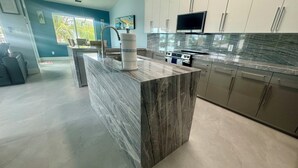 A modern kitchen with marble countertops, stainless steel appliances, and a large island.