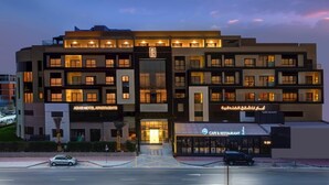A multi-story hotel with a cafe and restaurant on the ground floor, multiple balconies, and a well-lit entrance. - Abar Hotel Apartments (Dubai)