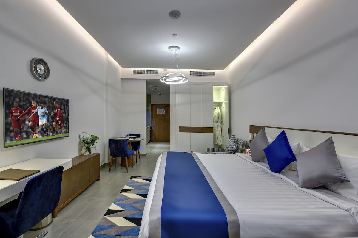 A modern hotel room with a bed, desk, and seating area.