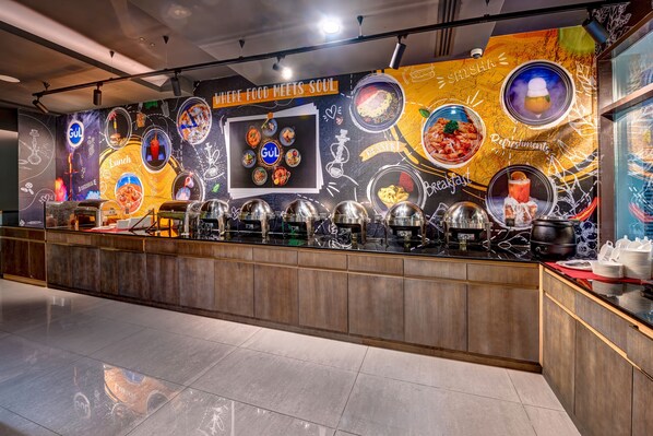 A buffet area with a variety of food options and a mural with food-related illustrations. - Abar Hotel Apartments (Dubai)