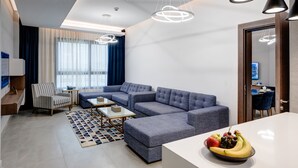 A modern living room with a sectional sofa, a small table, and a fruit bowl. - Abar Hotel Apartments (Dubai)