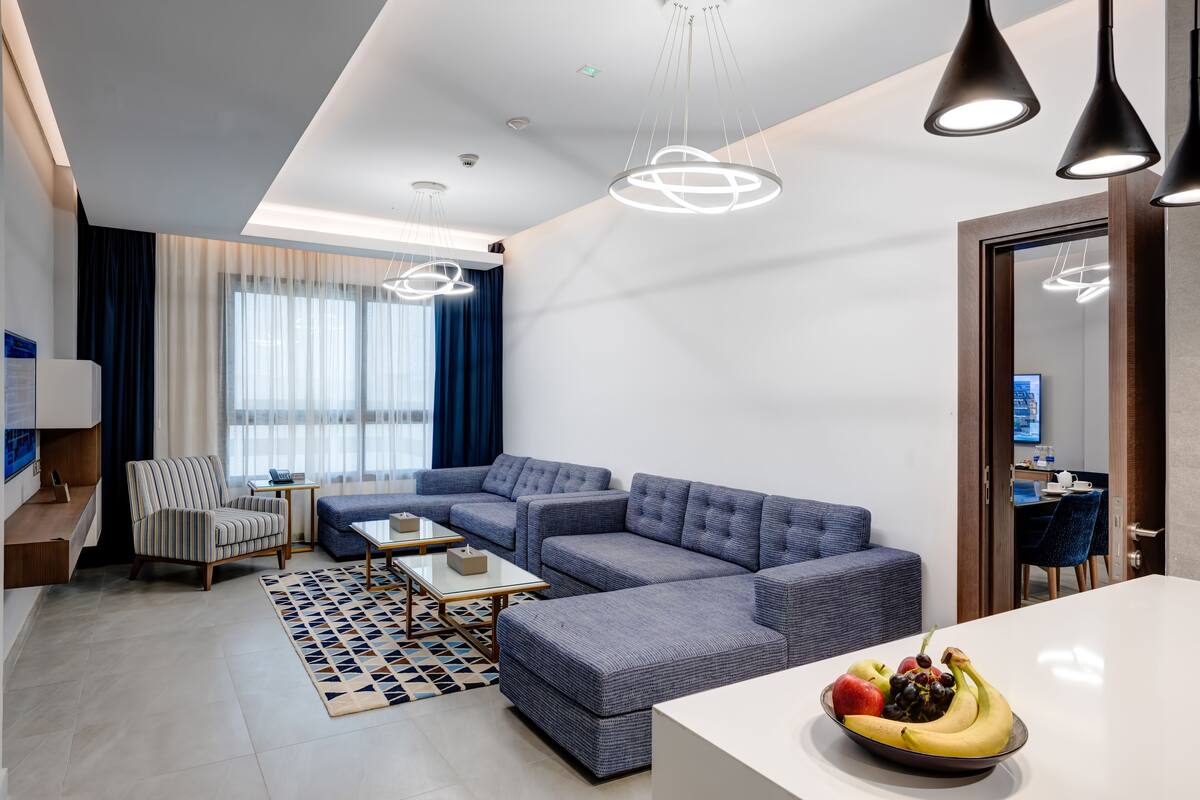 A modern living room with a sectional sofa, a small table, and a fruit bowl.