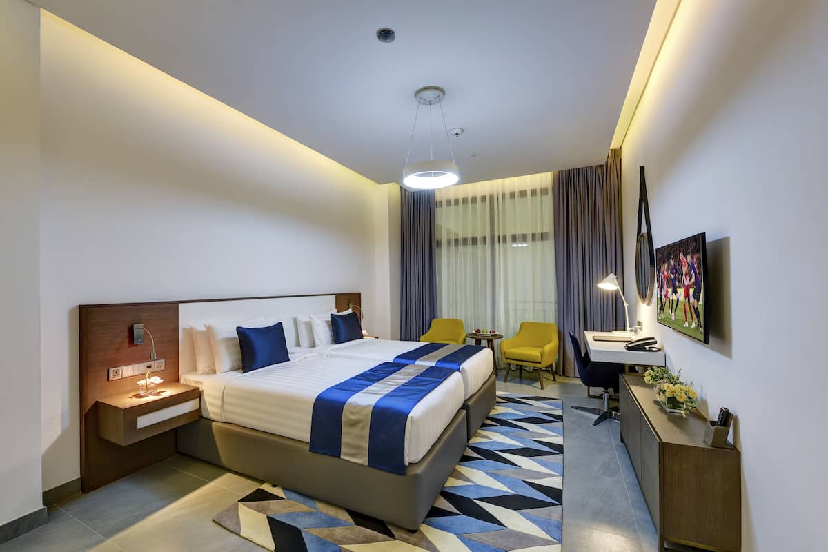 A modern hotel room with a large bed, bedside tables, a desk, and a chair.