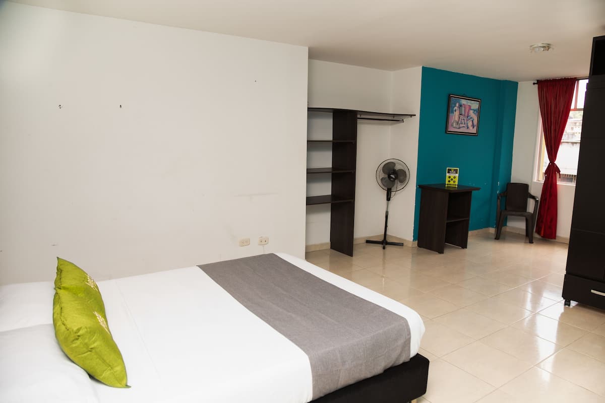 Ein Hotelzimmer mit einem Bett, einem Schreibtisch, einem Stuhl und einem Ventilator.