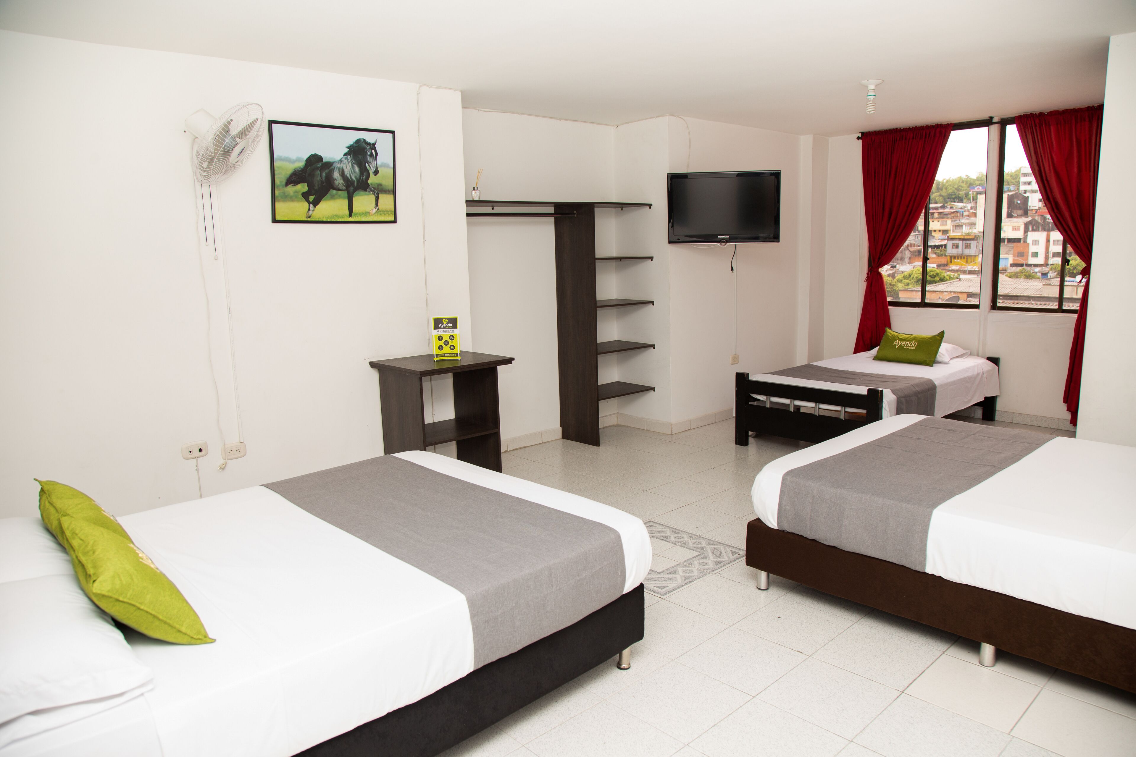 Habitación de hotel con dos camas, televisión, armario y ventana con cortinas.