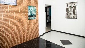 A hallway with a brick wall, a tiled floor, and two framed pictures. - Ayenda Quimbaya de Oro 1903 (Armenia)