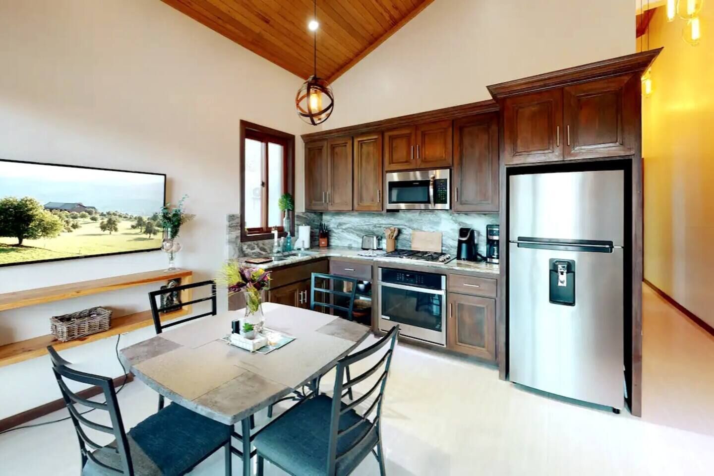 A modern kitchen with wooden cabinets, stainless steel appliances, and a dining area with a table and chairs.