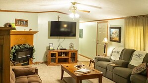 Una sala de estar con televisión, sofá, mesa de centro y chimenea.