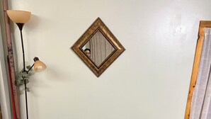 Un sofá cama marrón con un reposapiés a juego, una mesita con lámpara y un espejo en la pared.