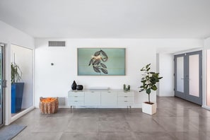 A modern interior with a white console table, a large abstract painting, and a potted plant. - Mid - Century Retreat (Palm Springs)
