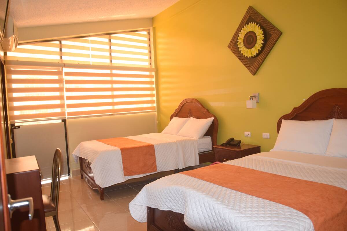 A hotel room with two beds, a desk, and a chair.
