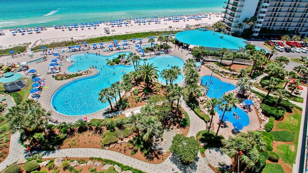 Un resort con varias piscinas, una playa y un gran edificio de hotel.