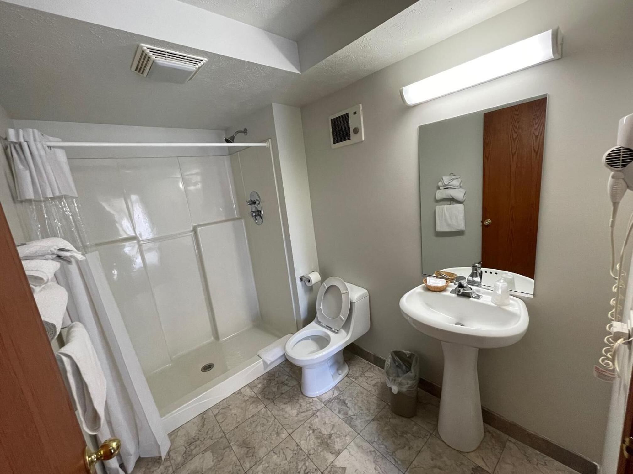 A bathroom with a glass-enclosed shower, a toilet, a sink, and a hairdryer.