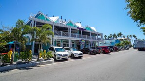 A building with a green and white facade, multiple balconies, and a sign that reads "DMCURTINDA". - Island Retreat by SeaBreeze Vacation (Holmes Beach)