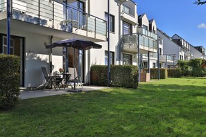 A modern apartment complex with outdoor seating and a well-maintained lawn. - Haffblick Whg. Ha03, Deutschland (Ostseebad Boltenhagen)