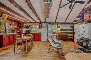 A spacious kitchen with wooden beams, a dining area with a table and chairs, and a cozy seating area with two chairs.