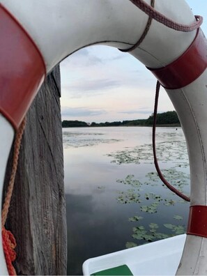 A boat with a white and red structure, a rope, and a calm water body with lily pads.