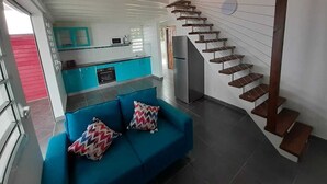 Ein modernes Wohnzimmer mit einem blauen Sofa und einer Wendeltreppe.