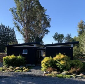 Stylish two-story building with a flat roof, glass door entrance, and a beautifully maintained garden.