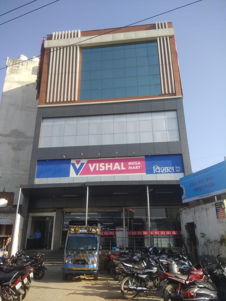 Un immeuble commercial avec une grande enseigne indiquant « VISHAL MEGA MART » et « CLARKS INN EXPRESS » au rez-de-chaussée.