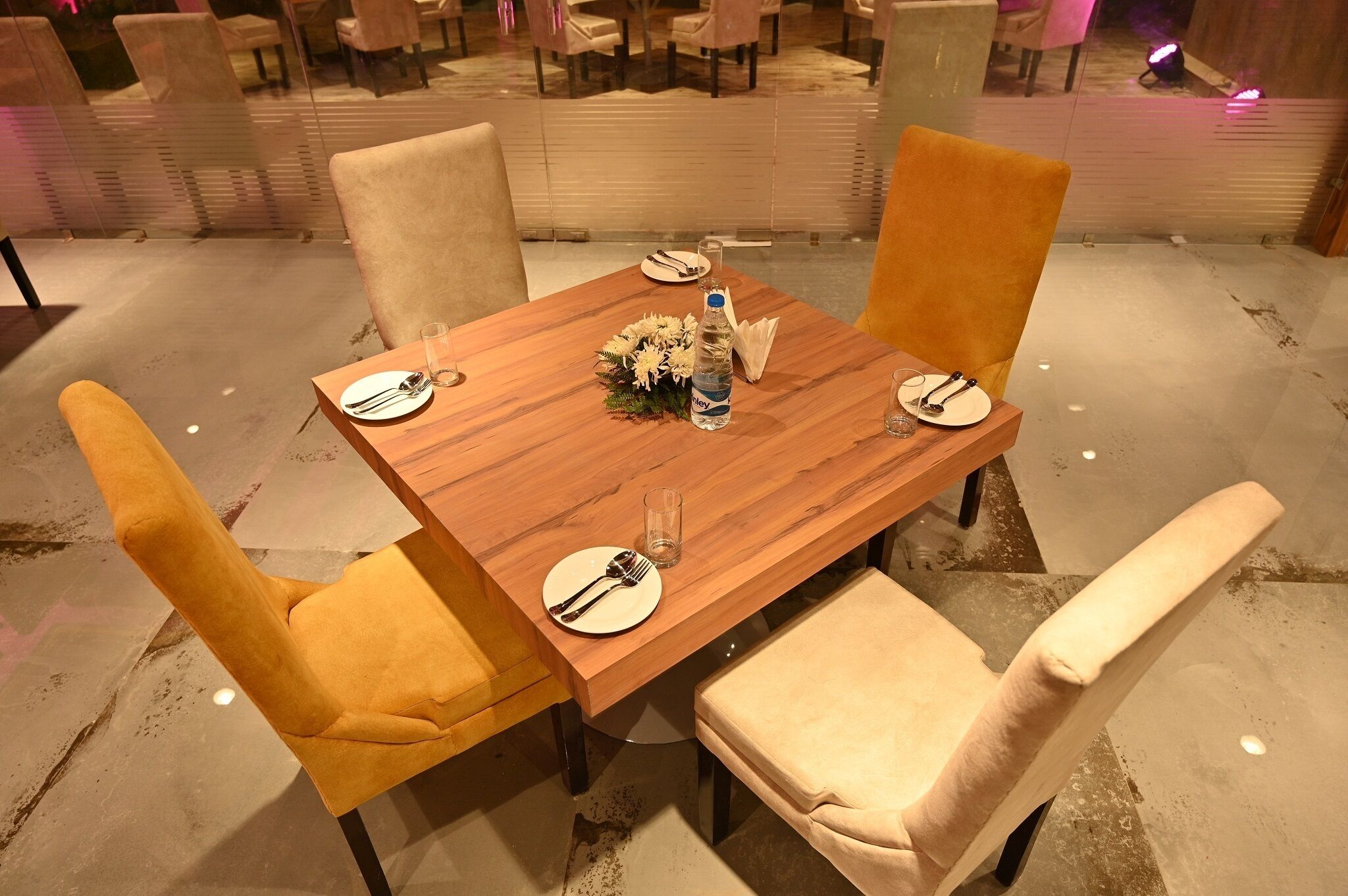 Une table à manger avec quatre chaises, une bouteille d’eau et une assiette avec des couverts.