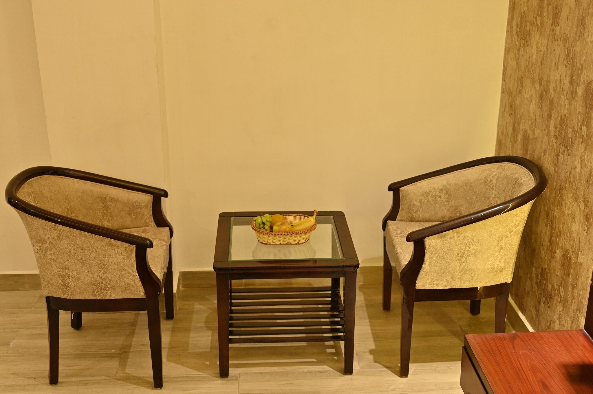 A room with two armchairs and a small table with a fruit basket.