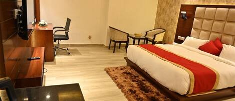 Una habitación de hotel con cama, escritorio, silla, televisor y control remoto.