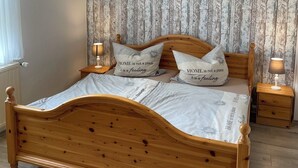 A wooden bed with a headboard, two bedside tables with lamps, and a patterned wallpaper.
