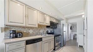 Una cocina moderna con electrodomésticos de acero inoxidable, armarios color beige y un salpicadero de azulejos.