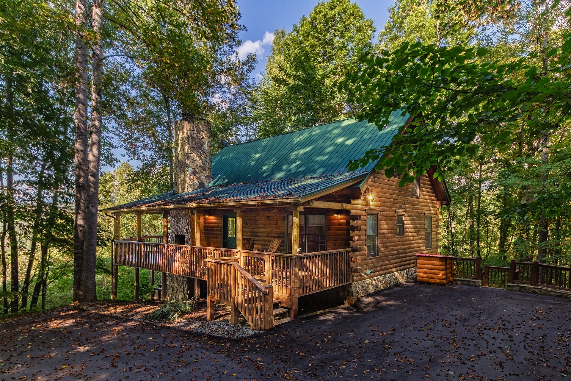 Une cabane en rondins dotée d’un porche et d’une terrasse couverte, entourée d’arbres.