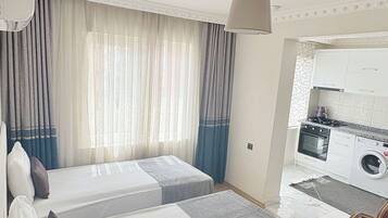 A hotel room with two beds, a kitchenette, and a dining area.