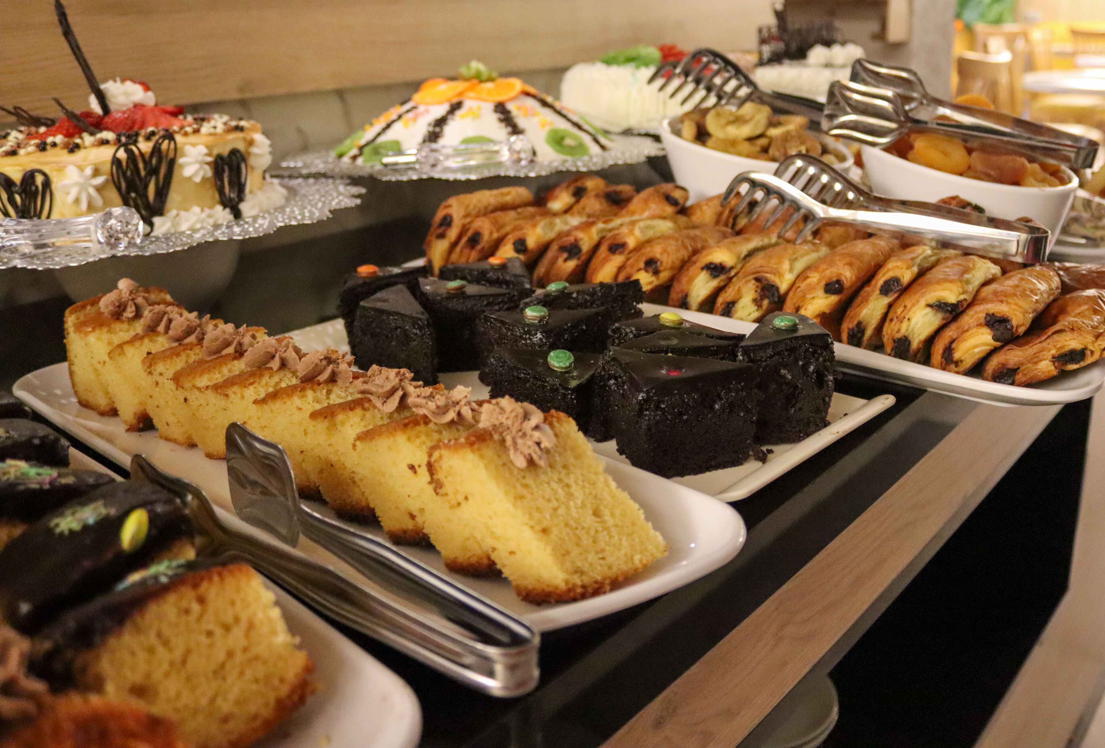 A buffet with various desserts including cakes, pastries, and bread.