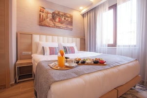 Una habitación de hotel con una cama grande, una mesita de noche, un cuadro en la pared y una ventana con cortinas.