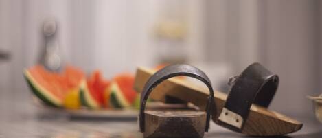 A rustic wooden teapot with a metal handle on a reflective surface.