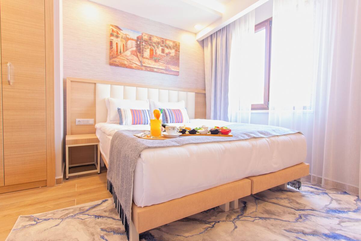 A hotel room with a large bed, a bedside table, a wardrobe, and a painting on the wall.