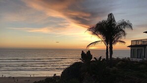 A sunset view over the ocean with a palm tree and a building on the right. - Great Location/Easy Beach Access/Walking Distance to Downtown Pier Area (Pismo Beach)