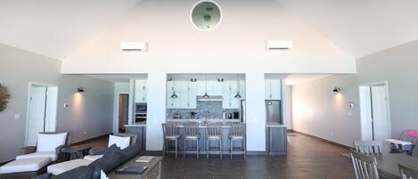 A spacious living area with a dark wood floor, a large gray sectional sofa, and a dining table with chairs.