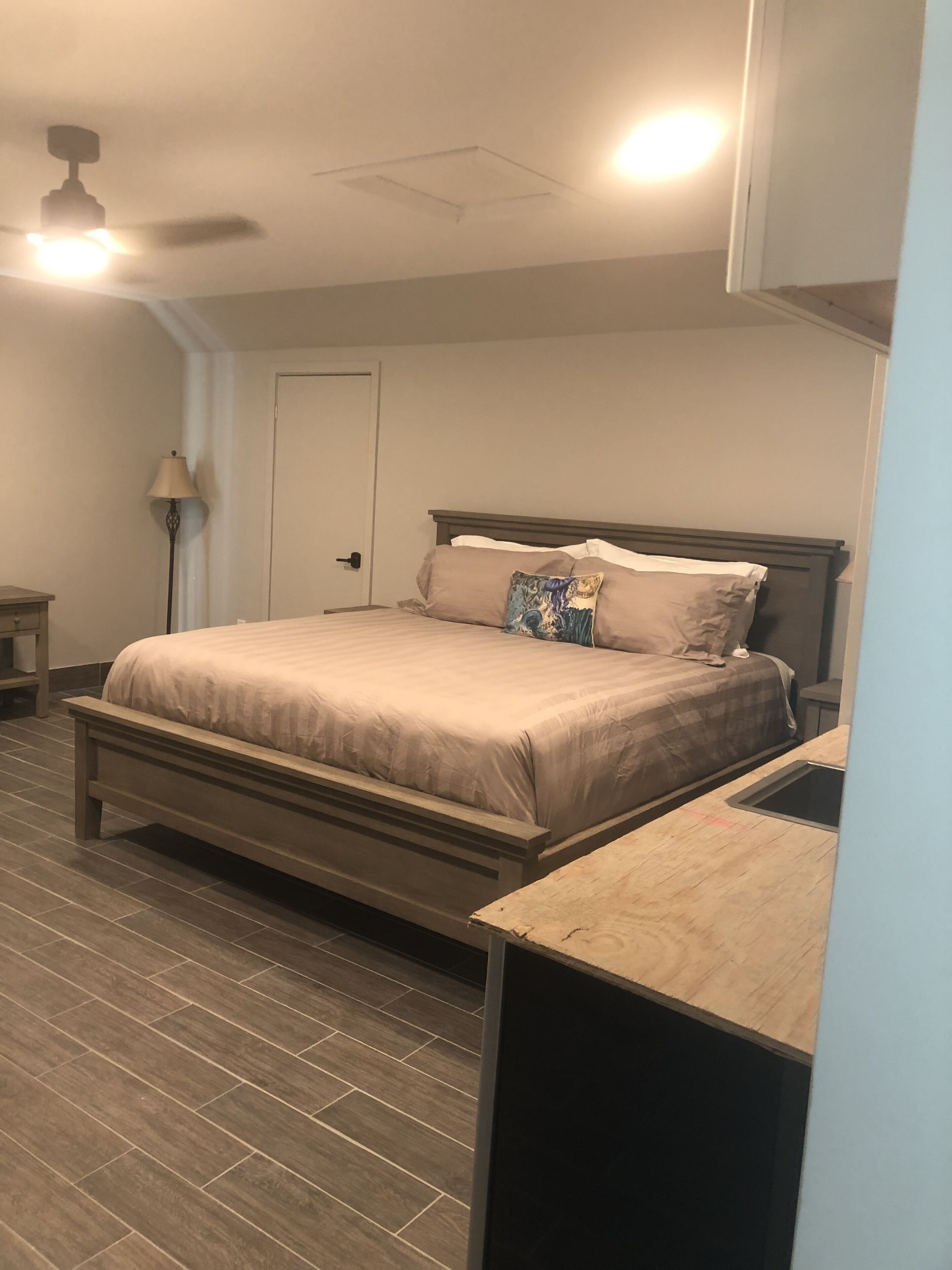 Un dormitorio con cama, mesita de noche, lámpara y ventilador de techo.