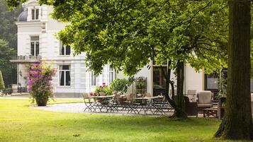 Een groot, elegant gebouw met een verzorgde tuin en een terras.