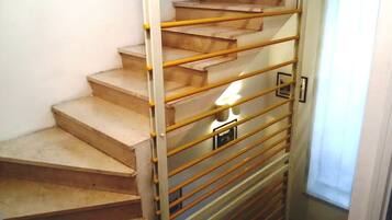 Un escalier doté d’une rampe métallique et d’un luminaire situé en bas.