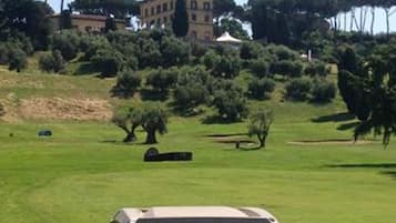 Ein Golfmobil auf einer Grünfläche, im Hintergrund ein Gebäude.