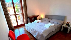 A bedroom with a bed, bedside table, lamp, and a chair.