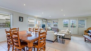 A spacious living area with a dining table, chairs, a sofa, and a TV. - Centrally located & lovingly maintained family home (PORT FAIRY)