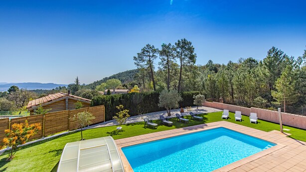Une piscine offrant une vue sur une forêt et des collines en arrière-plan.