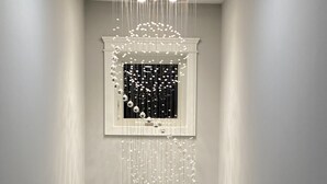 Un pasillo con una lámpara moderna y una obra enmarcada en la pared.